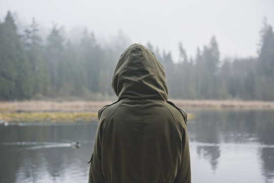 Woman wearing a parka and looking at the lake