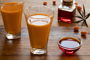 Two glasses of sea buckthorn juice, with sea buckthorn oil and berries