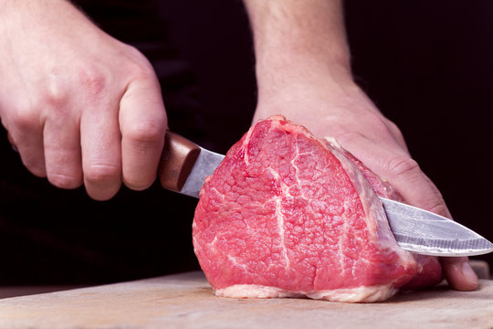 Butcher cutting beef meat on kitchen. Close-up