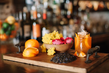 A colorful alcoholic rum cocktail with ingridients such as oranges, tumeric and black sesame seeds