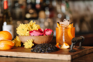 A colorful alcoholic rum cocktail with ingridients such as oranges, tumeric and black sesame seeds