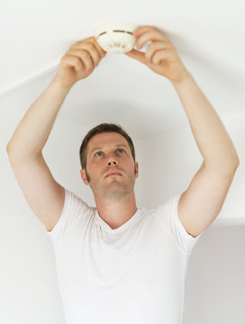 Male technician installing smoke detector at home.