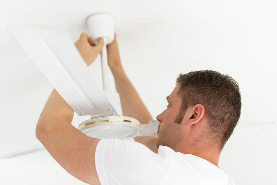 Male technician installing ceiling fan.