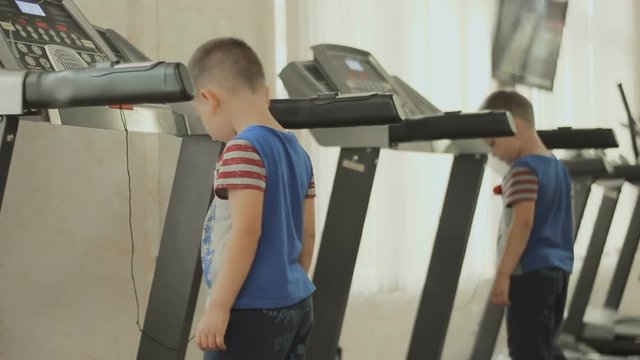 the child walks on the treadmill. the kid is exercising in the gym near the mirror. Boy cares about his body, figure, appearance and health from the childhood. The concept of a healthy lifestyle