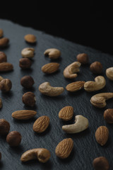 Variety of mixed nuts - almond, hazelnuts and cashew - on the dark slate background with copy space. Top view. Toned