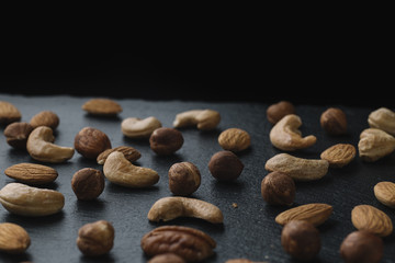 Variety of mixed nuts - almond, hazelnuts and cashew - on the dark slate background with copy space. Top view. Toned