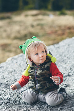 Cute Baby Boy Sitting on Gravel Looking Up