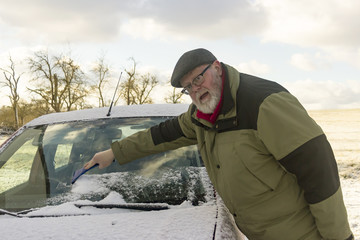 Senior befreit Autoscheibe von Frost und Schnee