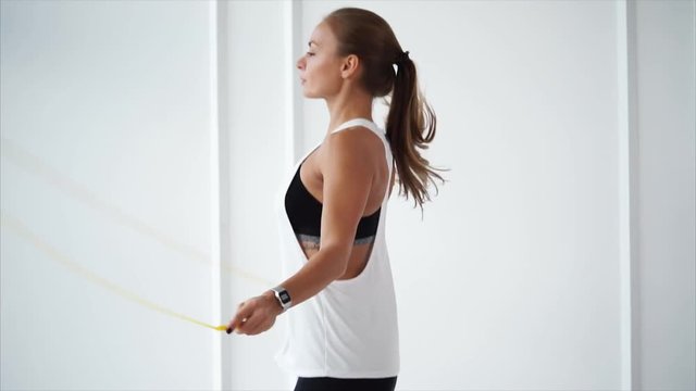 Profile view of girl is skipping rope in fitness hall. Keeping track of health and body and contemporary physical fitness.