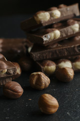 Chocolate bar pieces and nuts on dark background with copy space. Chocolate background. Toned