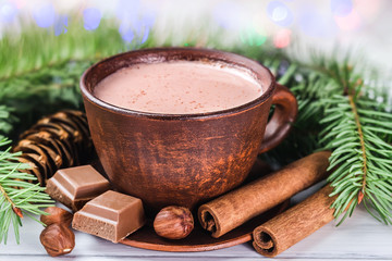 Blurred Christmas lights, cup of hot cocoa with milk, broken chocolate cubes, hazelnut and cinnamon...