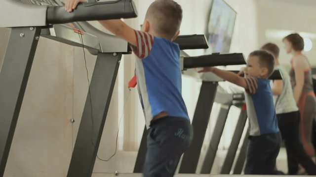 the baby walks on the treadmill. the kid is exercising in the gym near the mirror. Boy cares about his body, figure, appearance and health from the childhood. The concept of a healthy lifestyle