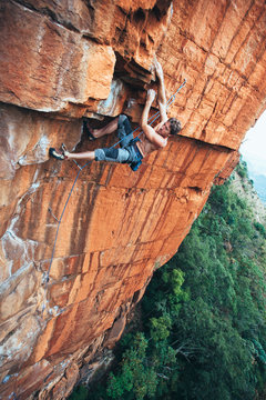 Fit rock climber climbing an extreme cliff face in a mountain