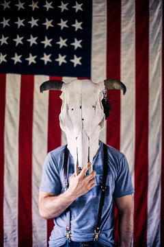 Man Holding A Bull Skull In Front Of An American Flag