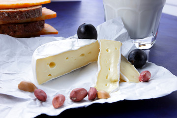 Camembert cheese, orange marble cheese, a glass of milk, pomegranate, olives, peanut grains, dark...