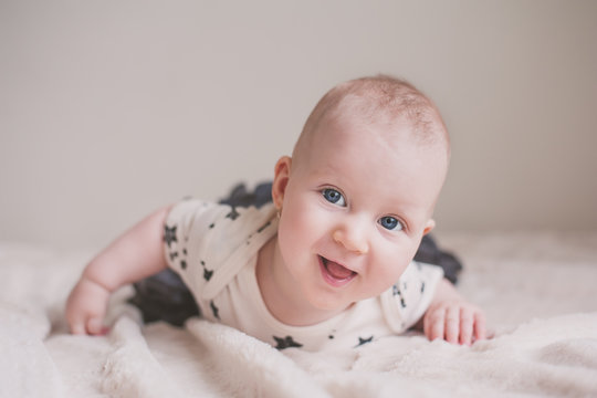 Adorable smiling baby lying on a bed and looking up curiously.