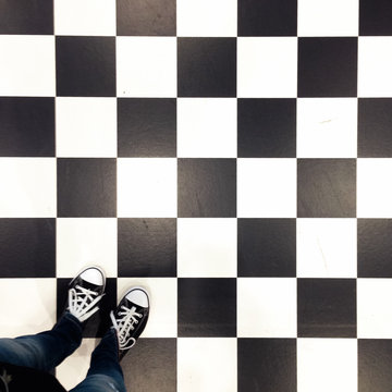Woman's feet on a black and white checkerboard tiled floor