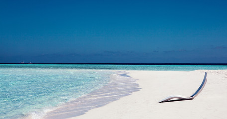 white sunbed near tropical calm beach with turquoise sea water and white sand. Maldives islands.