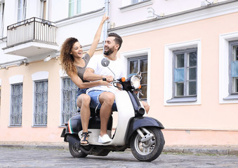 Fototapeta na wymiar Full length side view of happy couple riding on retro motorbike
