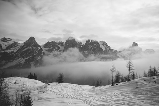 tracked powder slopes with snowcovered mountain range in the back - black and white