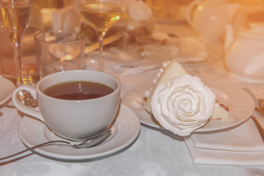 Hot tea in glass transparent Cup and a piece of cake decorated with a rose at the restaurant.