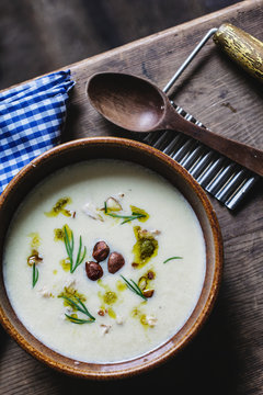 Celery root and hazelnut soup in rustic wooden table setting. Seen from above.