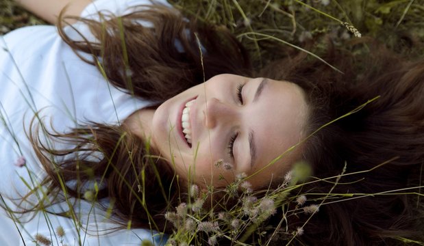 Girl is laying in the grass and flowers on the spring meadow