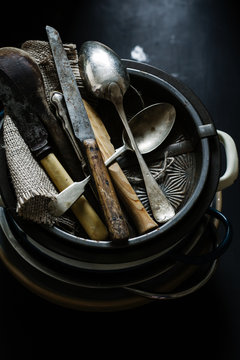 Vintage cutlery props in dark background. Natural light. Seen from above.