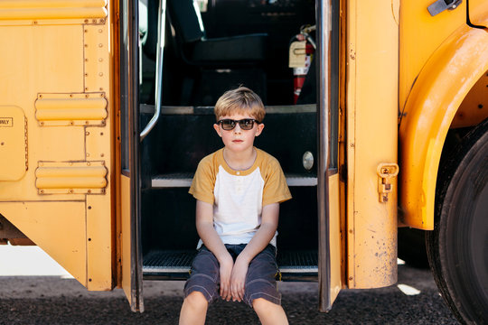 Boy sitting on the steps of a school bus
