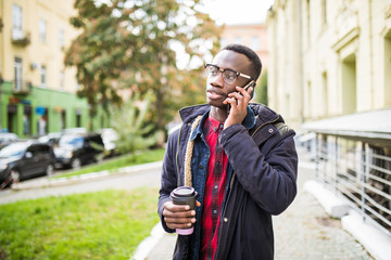 African american man speak his phone and holding a coffee on the street