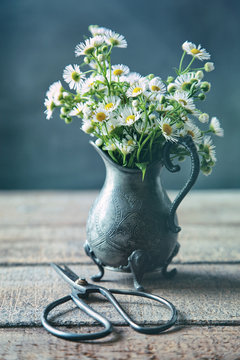 Wild daisies in pewter jug on table