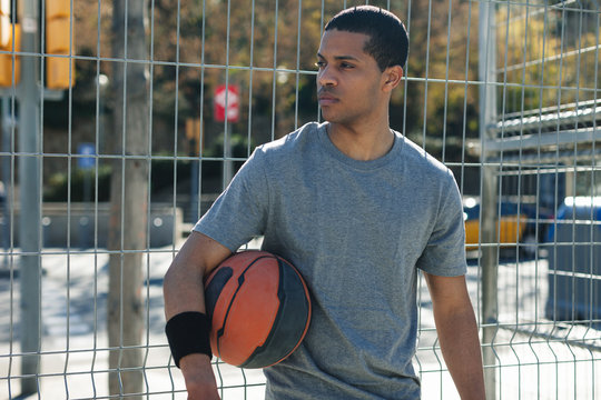 Portrait of a black male basketball player standing in an urban court.