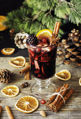 glass of hot mulled wine for the new year with ingredients for cooking, nuts and Christmas decorations