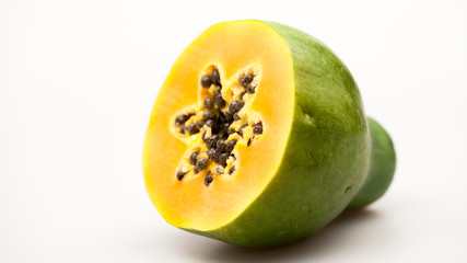 Papaya fruit - half and slice with seeds and light grey background
