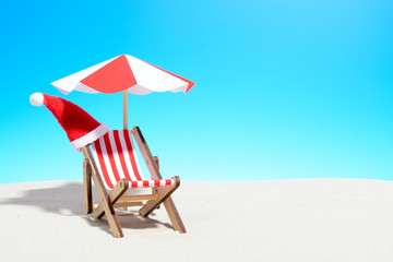 Merry Christmas on beach concept. Lounge chair with umbrella and Santa hat