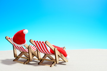 Merry Christmas on beach concept. Two lounge chairs with Santa hats