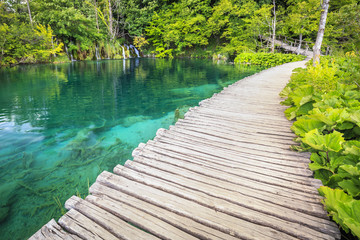 Fototapeta na wymiar Walking trail over blue water near waterfalls in a green forest. Plitvice lakes, Croatia