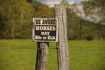 Horse may bite or kick warning caution sign on fence pasture field post
