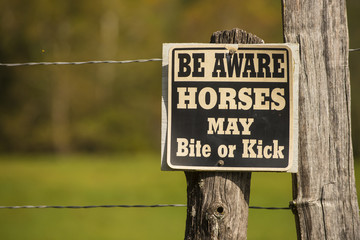 Horse may bite or kick warning caution sign on fence pasture field post