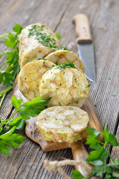 Deftiger bayerischer Serviettenknödel in Scheiben geschnitten und rustikal serviert – Sliced Bavarian bread dumpling  served on a  wooden cutting board