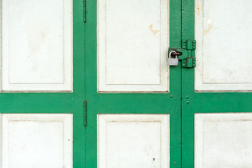 Closed up on vintage white and green wood door with silver lock.