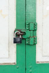 Closed up on vintage white and green wood door with silver lock.