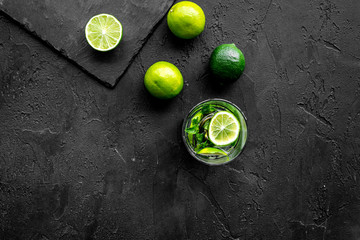 Glass of mojito, lime, mint on black stone background top view copyspace