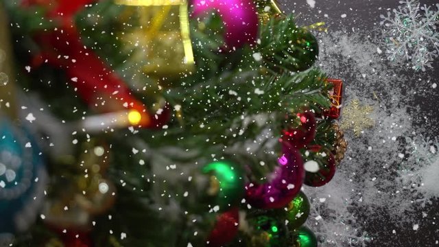 Greeting Season concept.Christmas tree and decorations with presents and ornaments on wood table from above with falling snow in 4k (UHD)