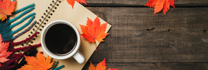 Autumn leaves and a cup of coffee with plaid on old vintage wooden background.