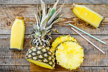 Freshly squeezed pineapple juice near fruit slices on wooden background top view