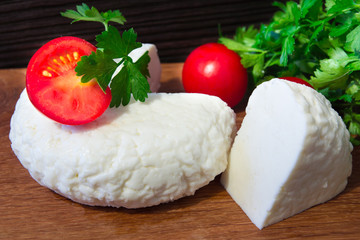 Young oak cheese cutting Board with tomatoes and parsley. Mozarella for pizzas and salads.