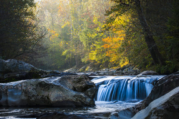 Smooth flowing water falling over rocks downstream in forested environment landscape scene