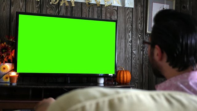 gry or happy millennial male watching generic sports game on green screen tv