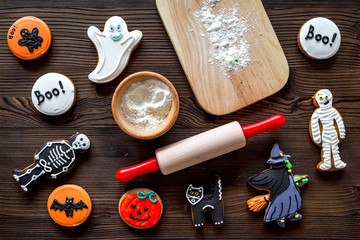 Cook halloween gingerbread cookies in shape of skeleton, mummy. Sweets near desk and rolling pin. wooden background top view copyspace